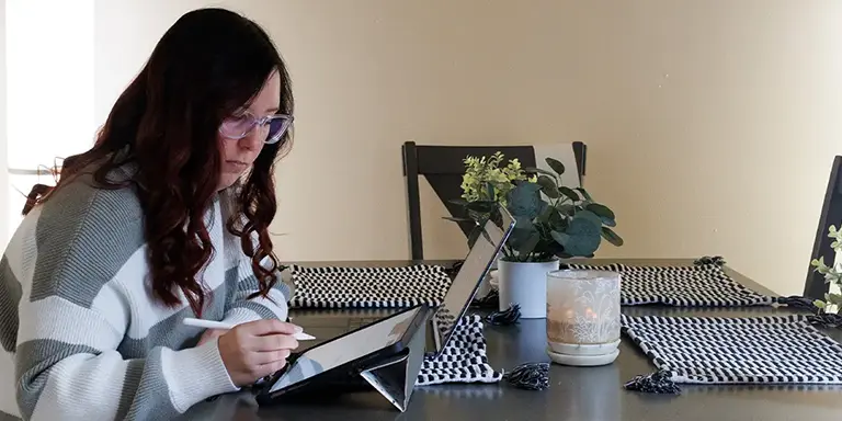 Woman sitting at a table looking at information on a tablet